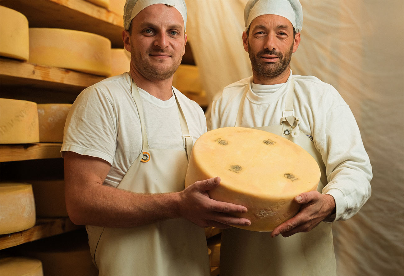 Due casari con in mano una forma di formaggio San Ste'